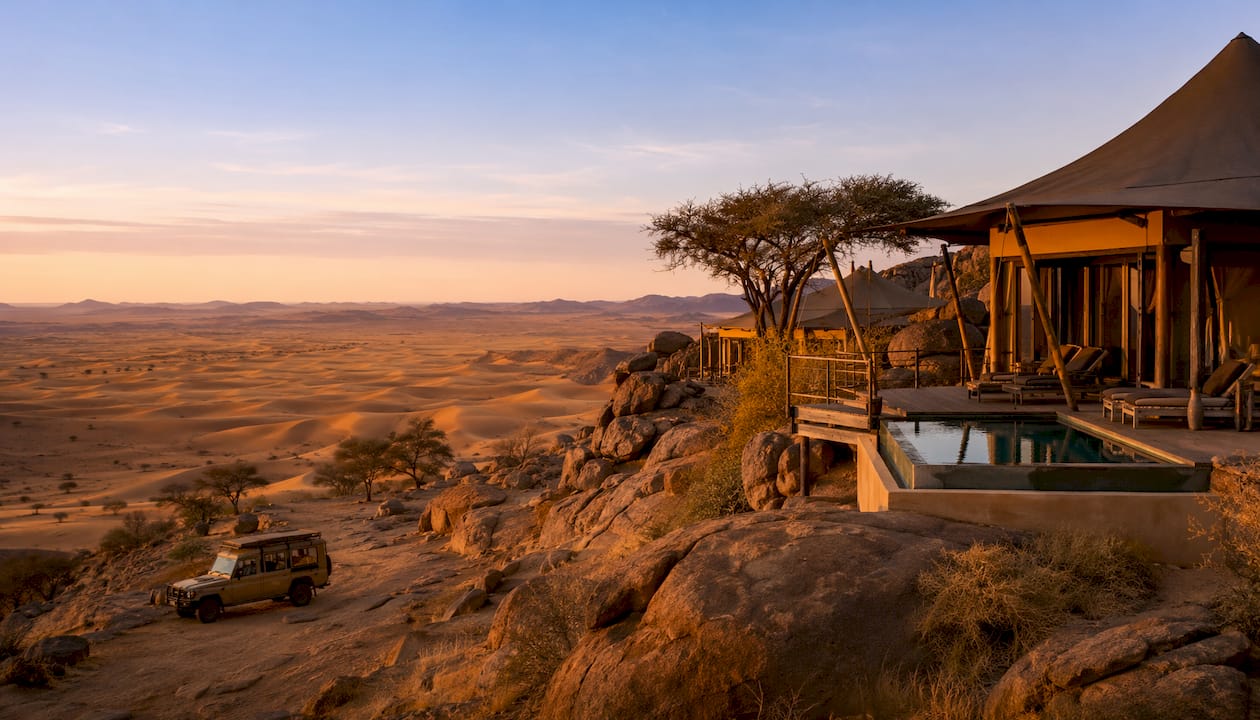 Luxury tented lodges among desert dunes at dusk