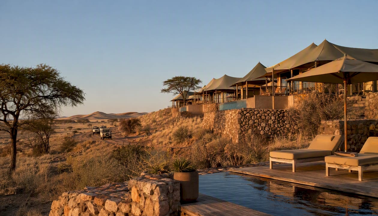 Luxury tented lodge overlooking golden desert dunes at dusk