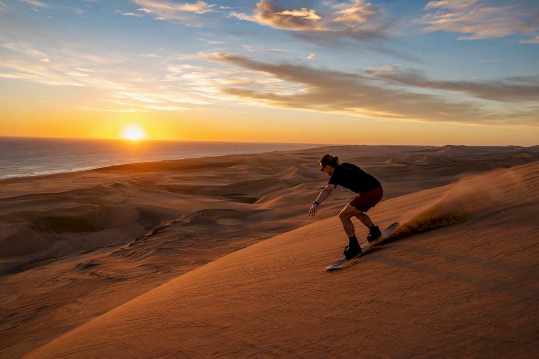 Person sandboarding on dunes near Swakopmund