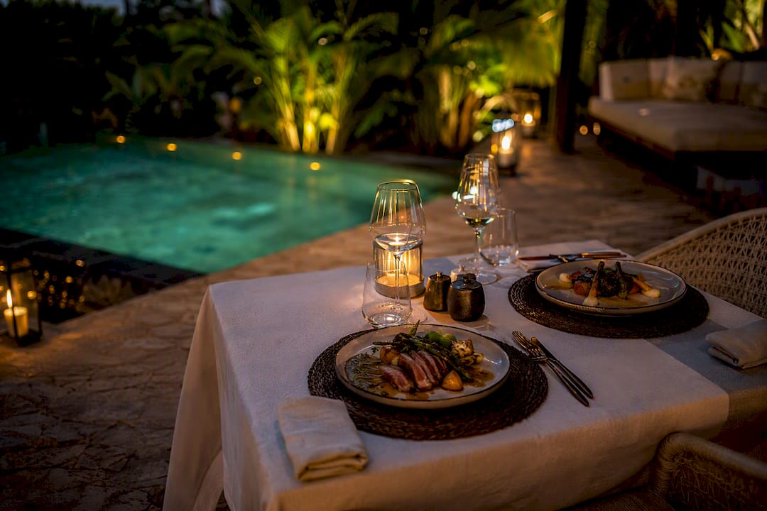 Outdoor luxury dining setup by safari waterhole at dusk