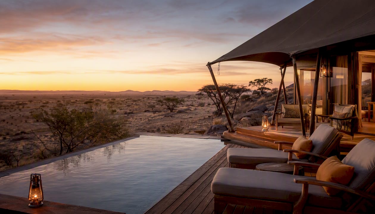 Luxury safari lodges at dusk with desert dunes