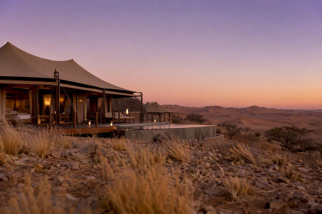 Luxury safari lodge with desert dunes sunset