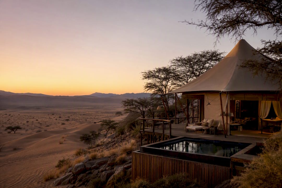 Luxury tented safari lodge with plunge pool in desert dunes at dusk
